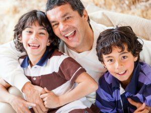 Father with sons smiling, laughing and hugging.