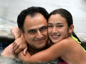 Milton Orthodontics Father and his Daughter hugging during a swim. Daughter is wearing metal braces and smiling.