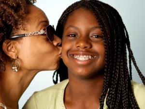 Milton Orthodontics Mother Kissing her daughter who is wearing ceramic braces   