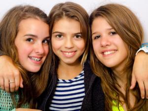 Milton Orthodontics Three Teen Girlfriends, hugging and smiling, one with braces   